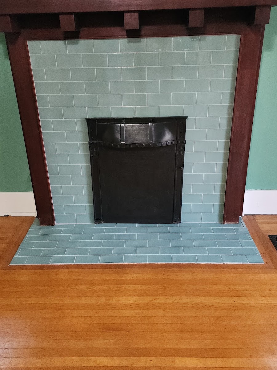 A craftsman-style fireplace surround retiled in sea-glass teal subway tile