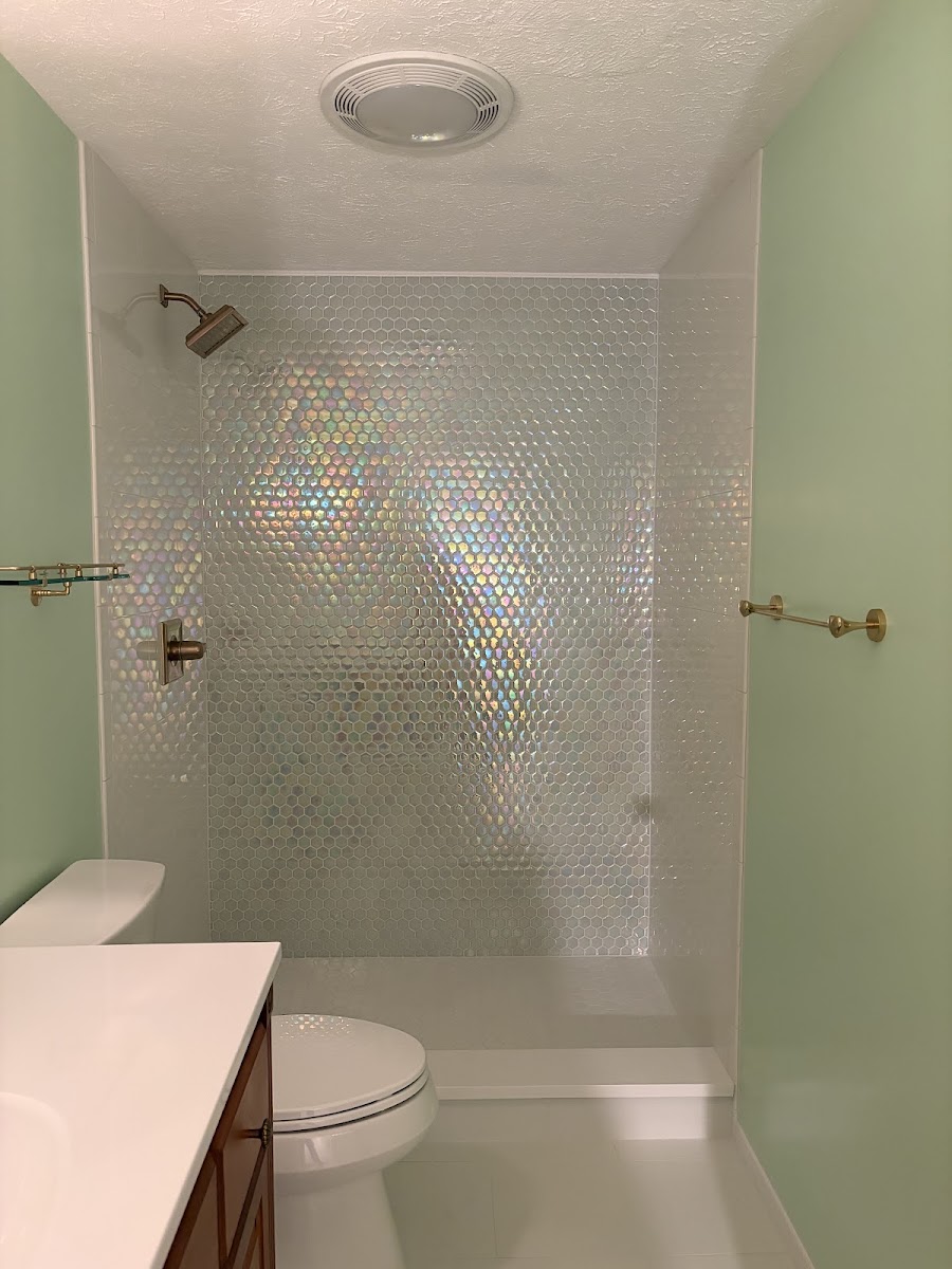A bathroom shower with iridescent pale hexagon mosaic tile and brass fixtures, installed by Imling Ceramic Tile